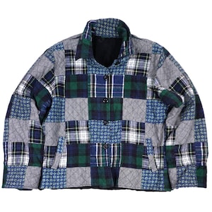 Puede incluir: Una chaqueta acolchada con un diseño de patchwork de cuadros azules, verdes y blancos y pequeños patrones geométricos. La prenda tiene cuello, mangas largas, un cierre frontal con cuatro botones oscuros y dos bolsillos laterales.