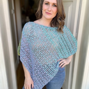 Può includere: Un poncho all'uncinetto con un gradiente di colori blu, verde e viola. Il poncho ha una trama sciolta e aperta e una forma leggermente svasata.