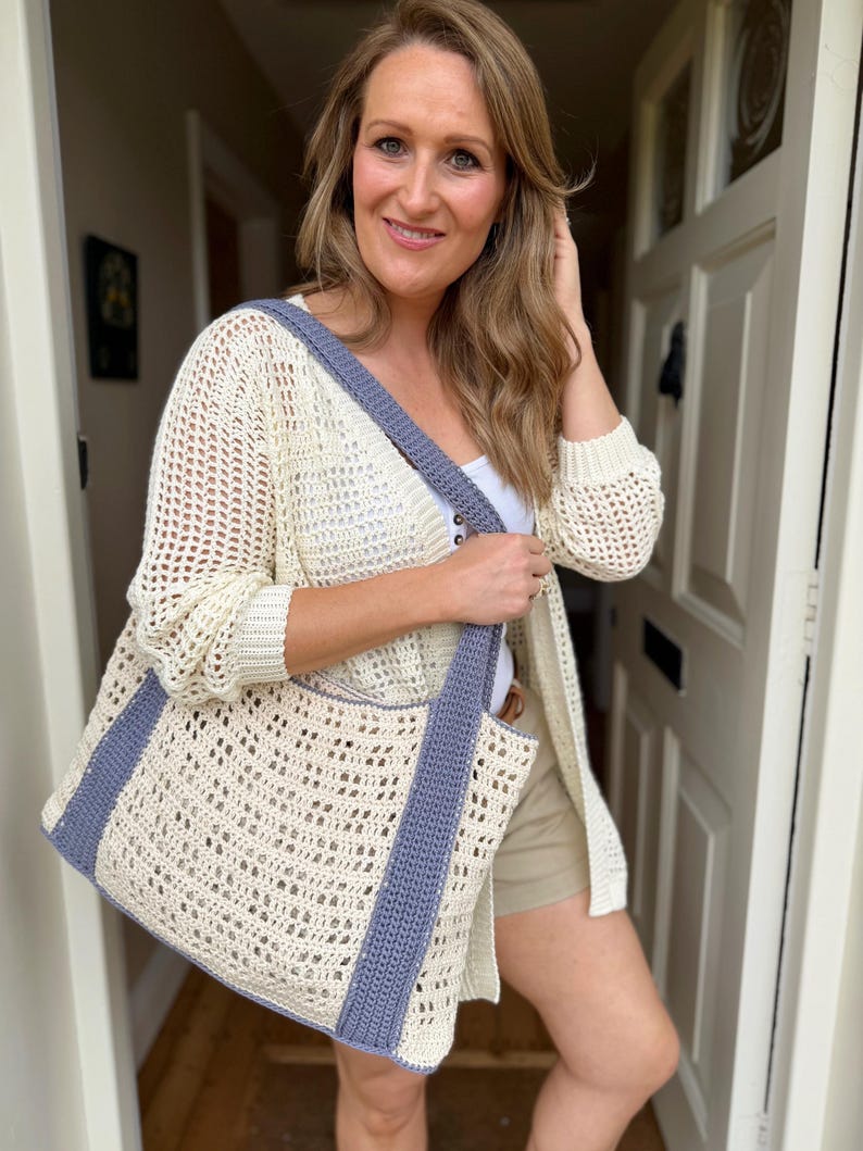 Puede incluir: Un bolso tote de ganchillo color crema con un patr&oacute;n calado en forma de rejilla y correas verticales de color azul pizarra s&oacute;lido que se extienden hasta formar las asas. El bolso tiene una base rectangular y un borde superior a juego.