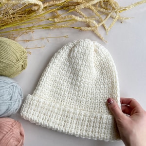 May include: A white crocheted beanie hat with a folded brim.
