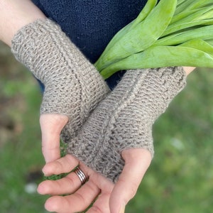 May include: A pair of brown knitted fingerless gloves with a textured stitch pattern.