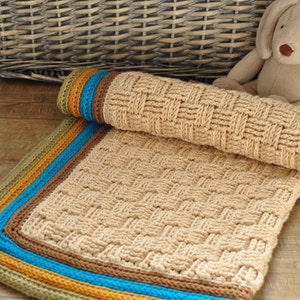May include: A crocheted baby blanket in beige with a woven pattern and a multi-colored border in shades of green, yellow, blue, and brown.