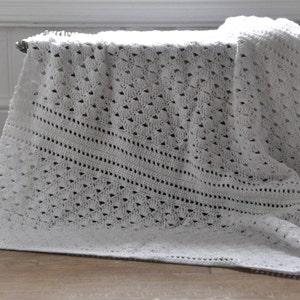 May include: A white crocheted baby blanket with a delicate openwork pattern.
