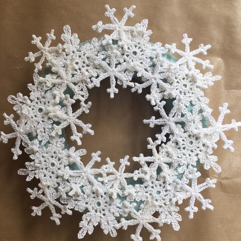 A crochet snowflake wreath on a brown background.
