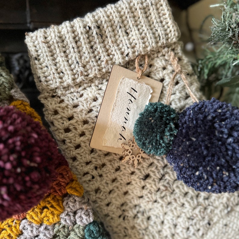 Close up of a crochet christmas stocking with a name tag and bauble.