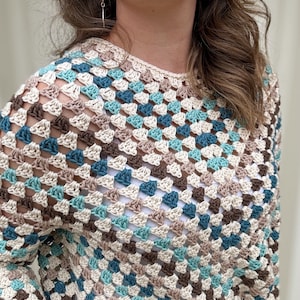 May include: A crocheted top with a geometric pattern in shades of brown, beige, teal, and blue.