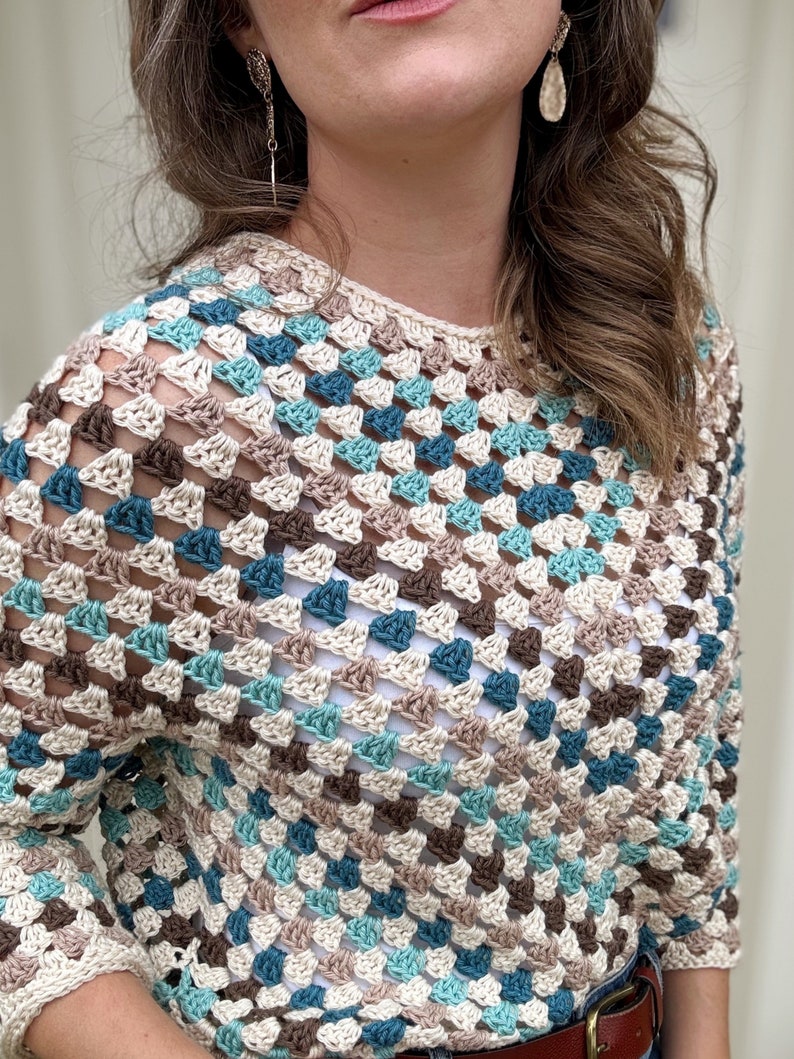 May include: A crocheted top with a geometric pattern in shades of brown, beige, teal, and blue.