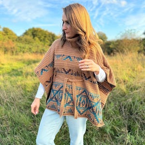 May include: A brown crocheted poncho with a geometric pattern in blue and teal. The poncho has a high neck and a belt.