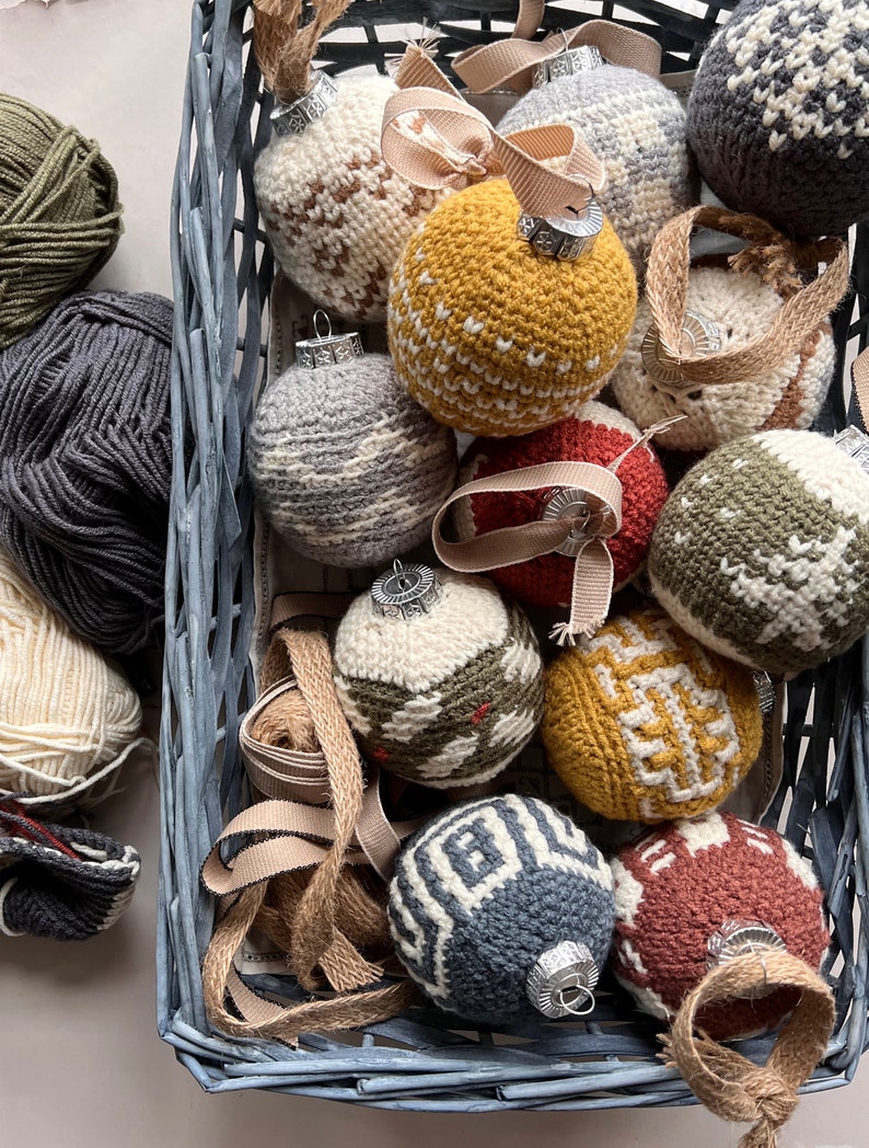 A collection of multicoloured rustic crochet baubles for a christmas tree in a blue basket.