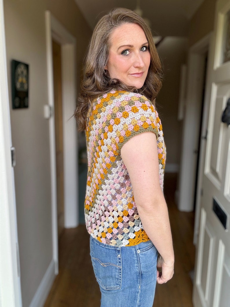 May include: A crocheted top with a granny square pattern in shades of pink, green, beige, and mustard yellow. The top has short sleeves and a scoop neck.