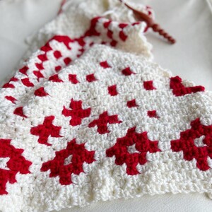 Close up of white and red yarn with a crochet hook.