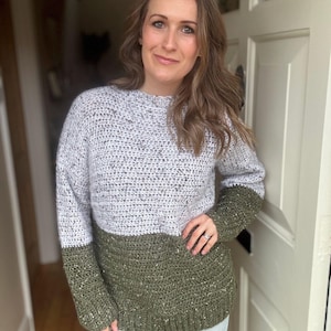 Puede incluir: Una mujer lleva un su&eacute;ter de crochet de dos tonos con la parte superior blanca y la inferior verde. El su&eacute;ter tiene una textura moteada.
