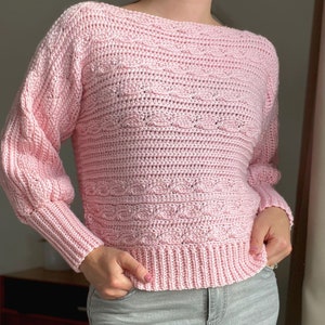 Woman in modern crochet sweater pattern with hands in pockets.