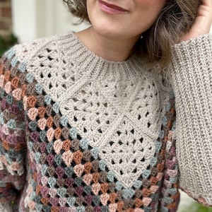Puede incluir: Un su&eacute;ter tejido a crochet con un patr&oacute;n geom&eacute;trico colorido. El su&eacute;ter tiene un cuello alto y mangas largas. El su&eacute;ter est&aacute; hecho con un hilo suave y tiene un ajuste holgado.