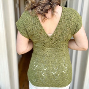 Puede incluir: Un top de crochet verde con un escote en V profundo y mangas cortas. El top tiene un delicado patr&oacute;n de calado.