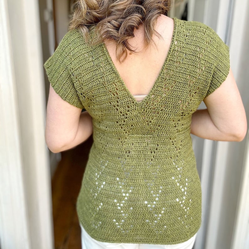 Puede incluir: Un top de crochet verde con un escote en V profundo y mangas cortas. El top tiene un delicado patr&oacute;n de calado.