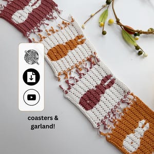 Op de afbeelding: Gehaakte paasgordijn en onderzetters met konijnenontwerpen in wit, bordeauxrood en oranje. De tekst "coasters & garland!" is zichtbaar. De slinger heeft franjes.