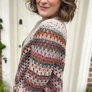 Puede incluir: Un top de crochet multicolor con un corte holgado y un escote amplio. El top est&aacute; hecho con una variedad de tonos de hilo marr&oacute;n, rosa y azul.