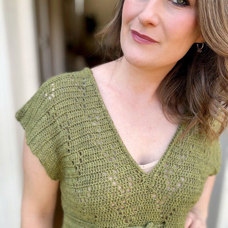 Puede incluir: Un top de crochet verde con cuello en V y mangas cortas. El top tiene un delicado patr&oacute;n de calado.