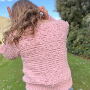 Pink crop crochet sweater pattern with cable detail on back.