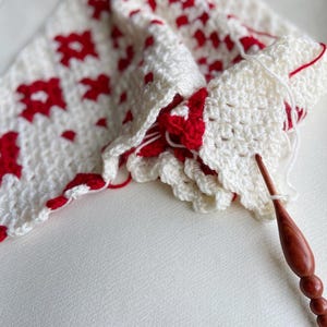 Close up of white and red yarn with a crochet hook.