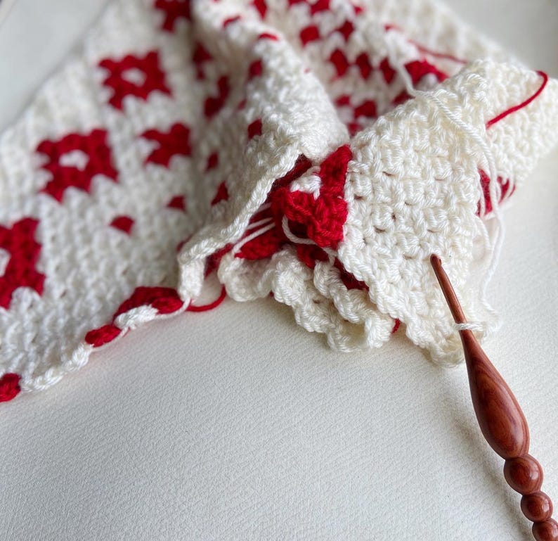 Close up of white and red yarn with a crochet hook.