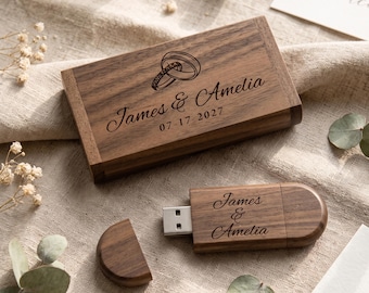 Könnte beinhalten: Eine rechteckige Schatulle aus dunklem Holz und ein passender USB-Stick aus Holz. Der Deckel der Schatulle ist mit zwei ineinander verschlungenen Ringen, den Namen James & Amelia und dem Datum 07-17-2027 graviert. Der USB-Stick trägt die Namen James & Amelia.