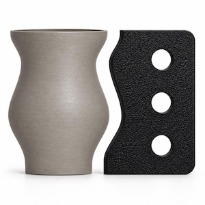 May include: A matte light gray vase with a curved, hourglass-like silhouette and a smooth texture, positioned next to a rectangular black tool featuring a wavy side edge and three circular cutouts with a textured, pebbled surface finish.