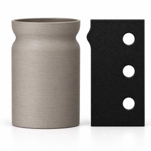 May include: A cylindrical light gray ceramic vessel with a slightly flared rim positioned next to a rectangular black metal plate featuring a textured finish and three circular cutouts arranged vertically along the right side of the object.