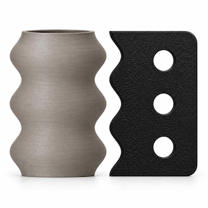 May include: A matte grey cylindrical vase with a wavy, undulating profile and a textured surface, positioned next to a flat, black rectangular tool featuring a wavy edge on one side and three circular cutouts arranged in a vertical line.
