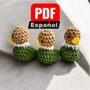 May include: Three small crocheted ducklings with tan heads, yellow beaks, white neck ruffs, and green bodies. Above the ducks is a red rectangular icon with the white text PDF and the black text Español below it on a white background.