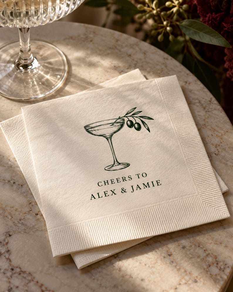 Cocktail napkin printed with a drawn coupe glass and Cheers to Alex and Jamie