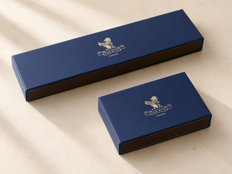 Concept mockup of navy matchboxes in 28cm and 14.5cm formats, featuring gold The Ritz London branding.