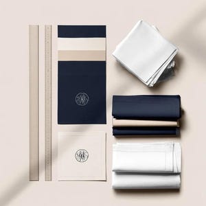 Square navy and cream cocktail napkins with small contrasting monogram letters, displayed with coordinating paper pieces. Digital concept mockup showing a personalised wedding or event table detail.