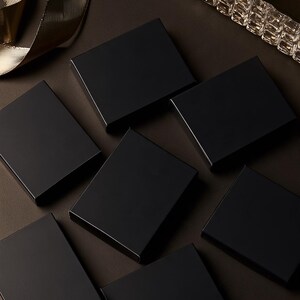Dark matchbox mockups styled for an evening celebration, with plain and gold-toned decorative sleeve designs. The presentation shows compact rectangular boxes for personalised party favours.