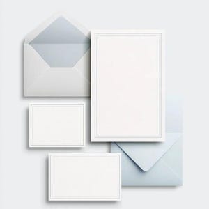 Unprinted cream invitation cards in several rectangular sizes with matching envelopes, arranged on a pale background. The mockup shows a coordinated wedding invitation, reply card and details-card format.