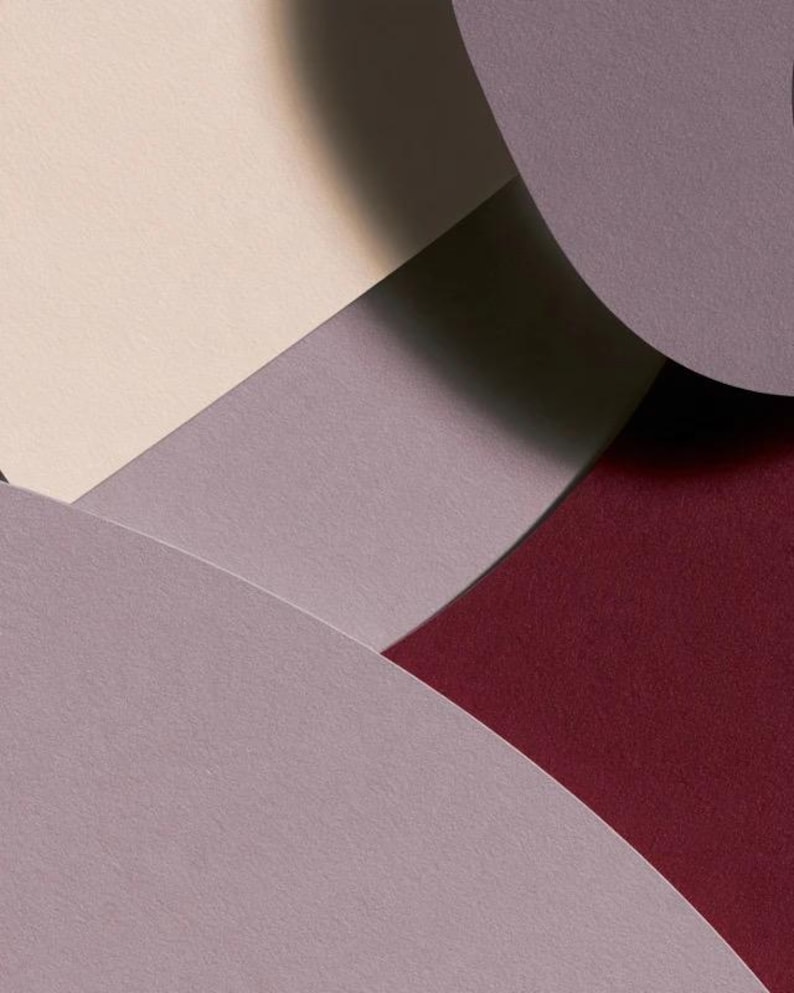 Layered unprinted menu-card mockups with curved paper edges in cream and muted burgundy tones. The arrangement shows contrasting paper shapes and soft shadows for a modern table-stationery design.