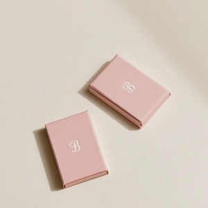 Contemporary matchbox mockup with a coloured paper sleeve and a clean graphic layout. The rectangular box is presented in soft directional light as a personalised wedding or event favour concept.