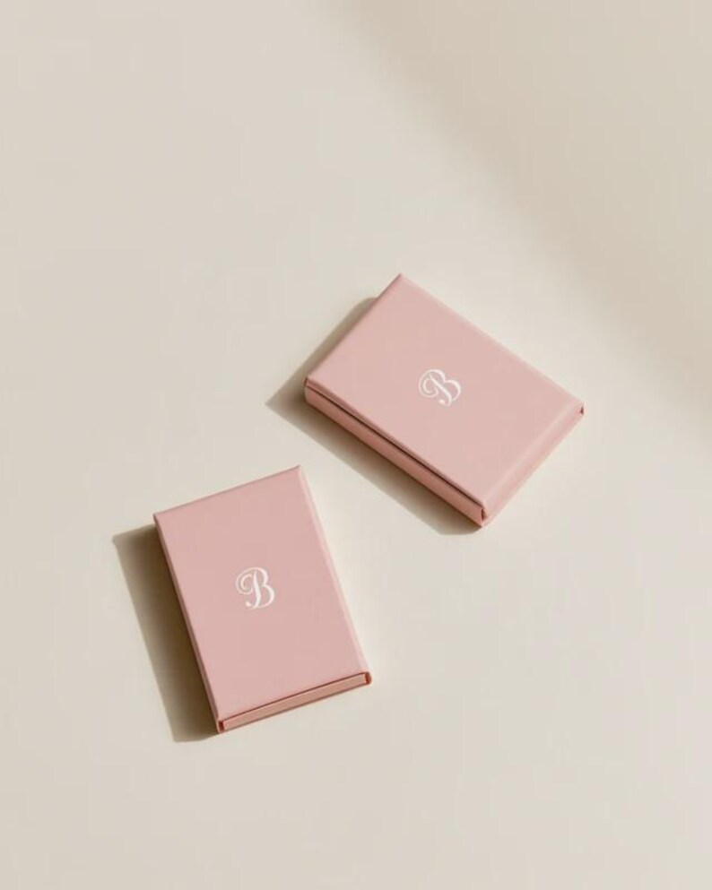 Contemporary matchbox mockup with a coloured paper sleeve and a clean graphic layout. The rectangular box is presented in soft directional light as a personalised wedding or event favour concept.