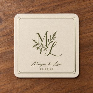 Digital tabletop mockup of one thin ivory square paper coaster with olive-green ML monogram, Maya and Leo names and date, lying on a simple walnut table. Standard printed wedding design example.