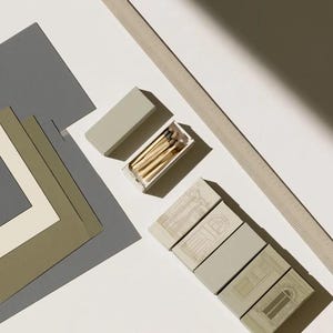 Cream rectangular drawer-style matchbox mockups arranged with coordinating neutral paper samples. The presentation shows sleeves, trays and the compact box proportions for bespoke event designs.