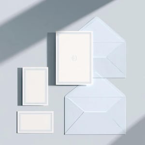 Unprinted cream invitation cards in several rectangular sizes with matching envelopes, arranged on a pale background. The mockup shows a coordinated wedding invitation, reply card and details-card format.