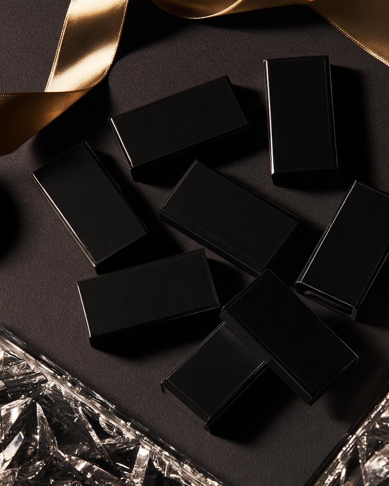 Dark matchbox mockups styled for an evening celebration, with plain and gold-toned decorative sleeve designs. The presentation shows compact rectangular boxes for personalised party favours.