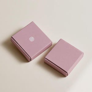 Contemporary matchbox mockup with a coloured paper sleeve and a clean graphic layout. The rectangular box is presented in soft directional light as a personalised wedding or event favour concept.