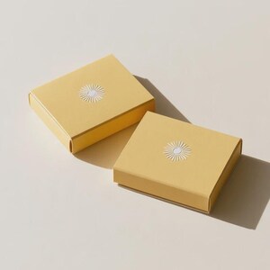 Contemporary matchbox mockup with a coloured paper sleeve and a clean graphic layout. The rectangular box is presented in soft directional light as a personalised wedding or event favour concept.