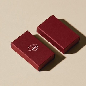 Contemporary matchbox mockup with a coloured paper sleeve and a clean graphic layout. The rectangular box is presented in soft directional light as a personalised wedding or event favour concept.