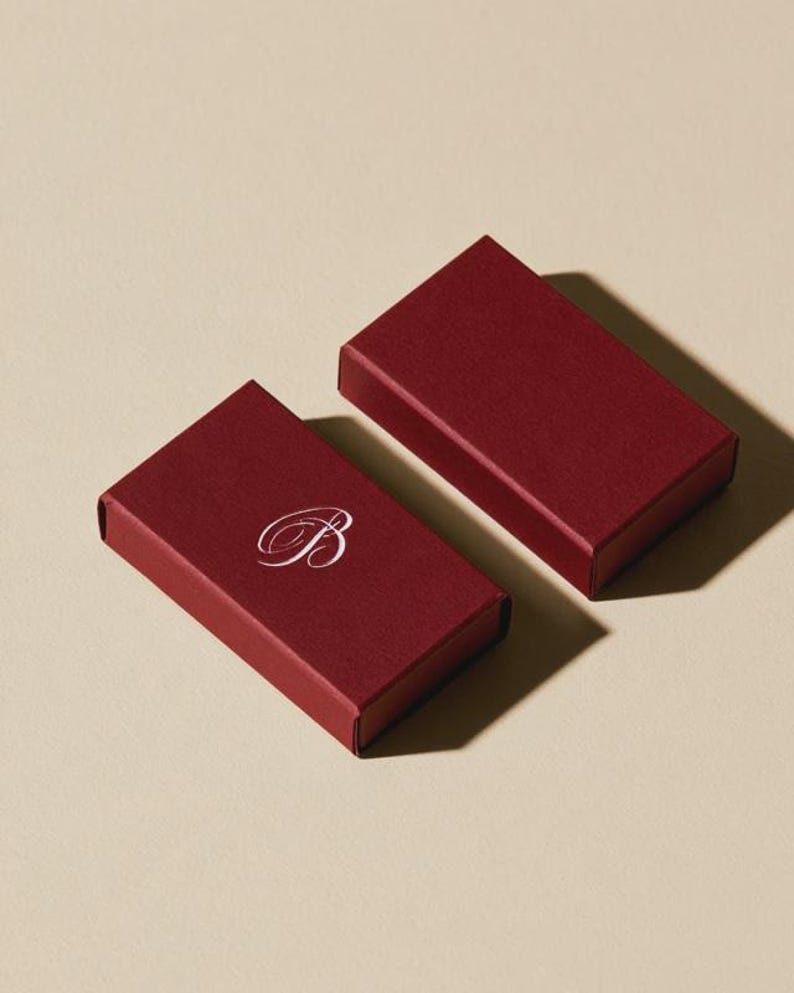 Contemporary matchbox mockup with a coloured paper sleeve and a clean graphic layout. The rectangular box is presented in soft directional light as a personalised wedding or event favour concept.