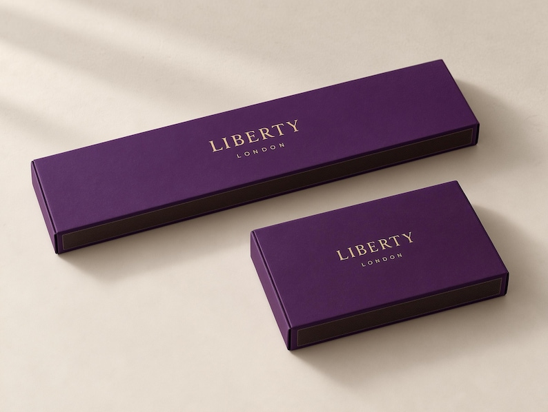Concept mockup of purple matchboxes in 28cm and 14.5cm formats, featuring gold Liberty London lettering.
