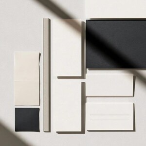 Cream rectangular menu cards and coordinated paper stationery arranged on a neutral background. Fine dark typography and generous margins create a restrained formal table-setting design. Digital concept mockup.