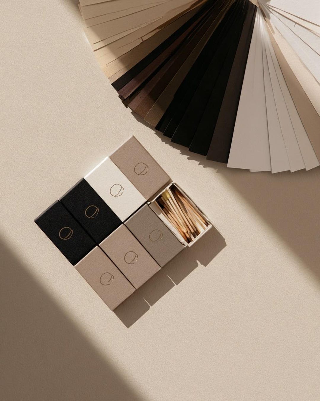 Black, white and stone monogram matchboxes beside a fan of colour swatches